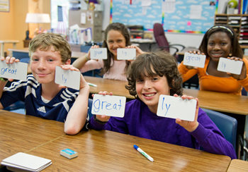 Students in classroom, holding up flashcards.