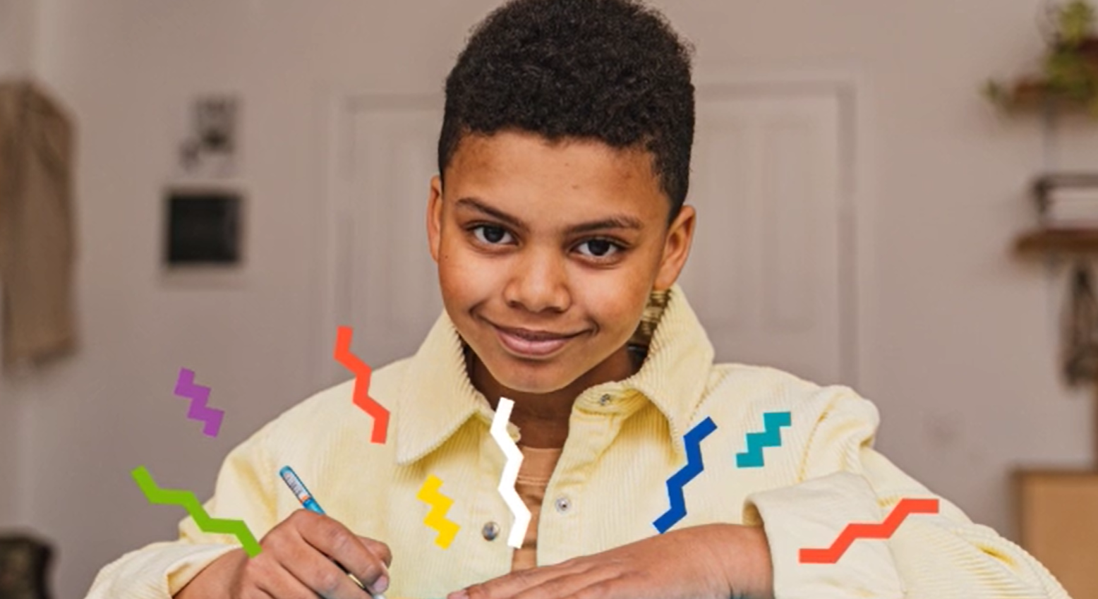 Child, writing and smiling at the camera.