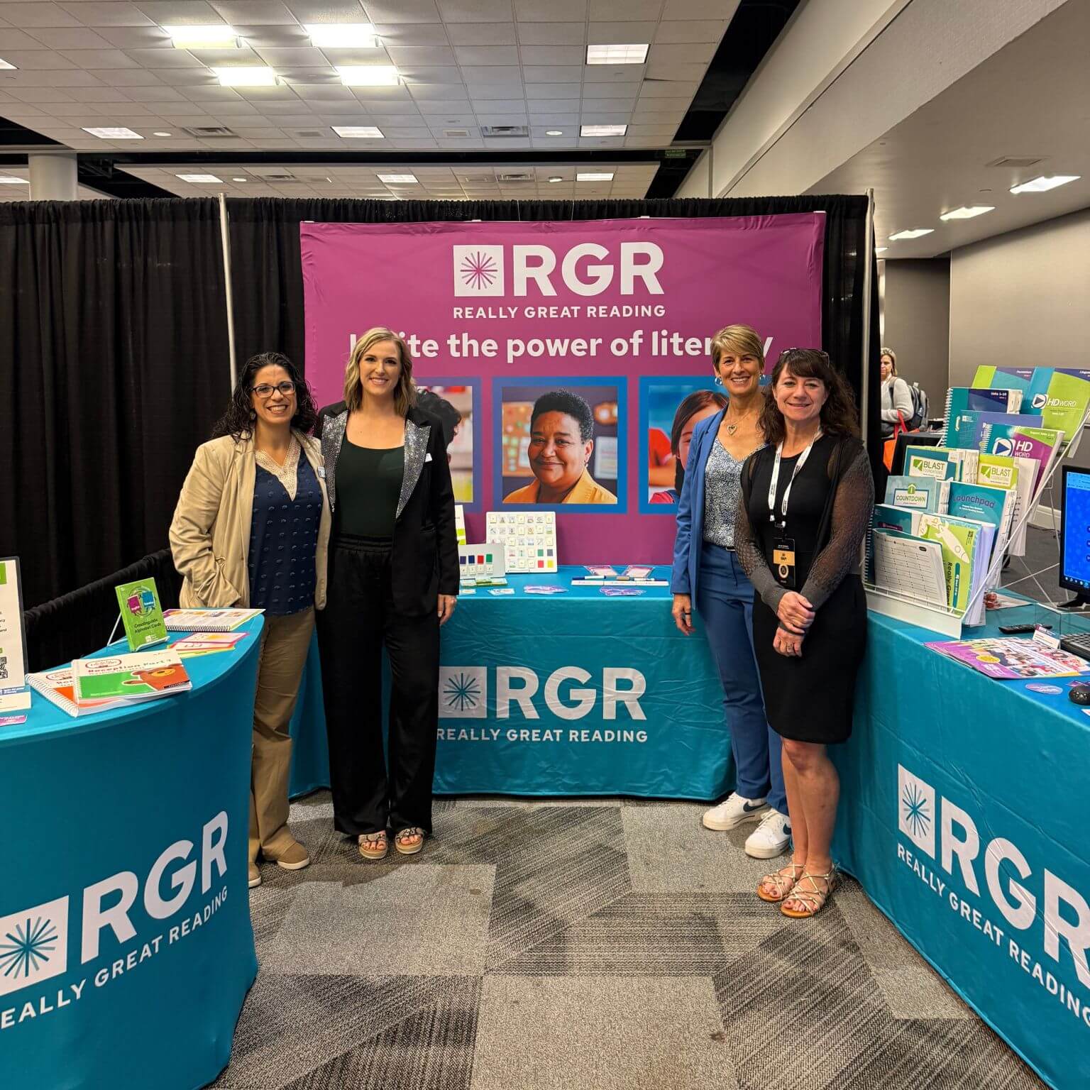 Four women standing in front of RGR tradeshow table.