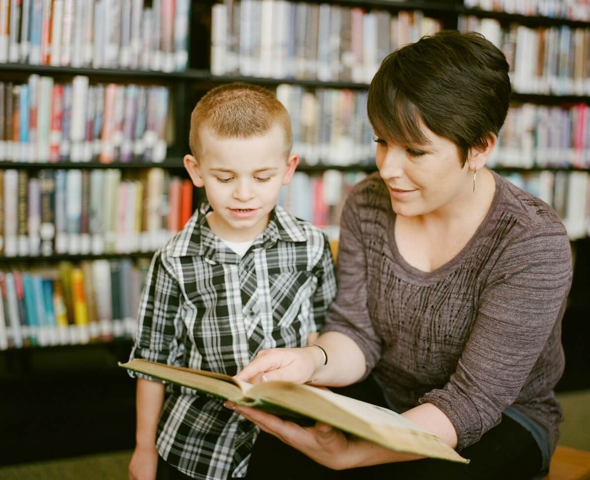 Adult with child looking in a book together.