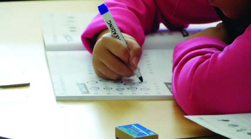 Close-up of child writing in workbook.