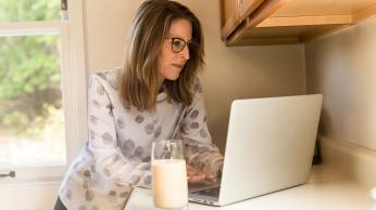 Woman using gray laptop computer in kitchen