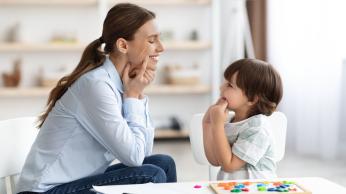 Teacher with student in a classroom practicing oral language.