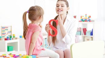 Teacher showing student how to pronounce letter S