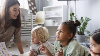 Woman with three children, teaching how to read.