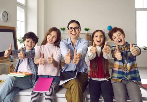 Teacher with students giving the thumbs up.