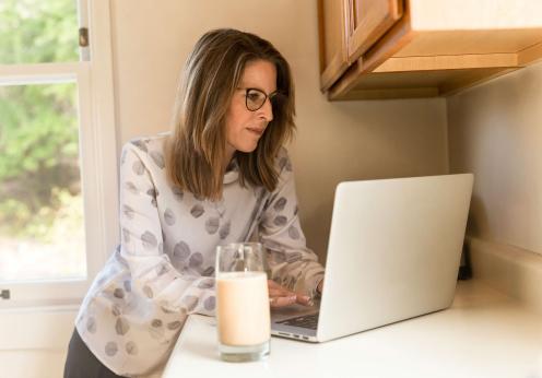 Woman using gray laptop computer in kitchen