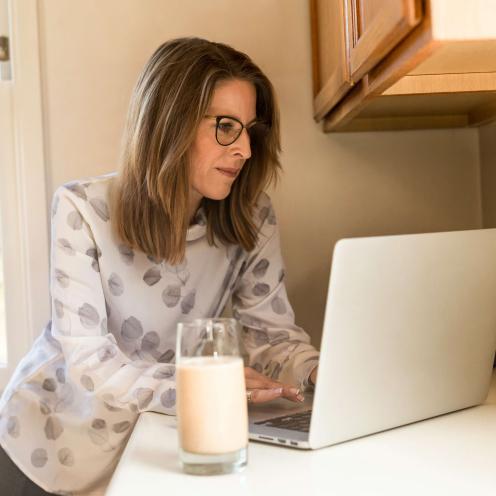 Woman using gray laptop computer in kitchen