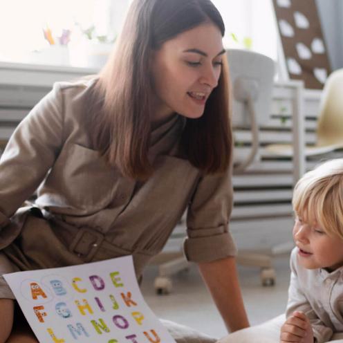 Teacher helping student with alphabet.