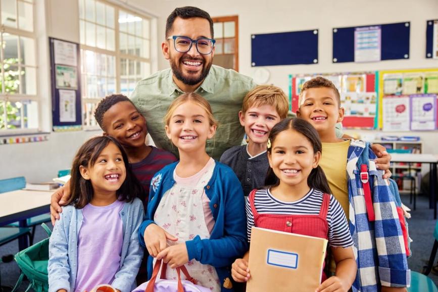 Students in classroom with teacher, posing for picture.